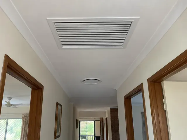 Ceiling return-air grille in a hallway with timber door frames and white plaster ceiling in Coombabah